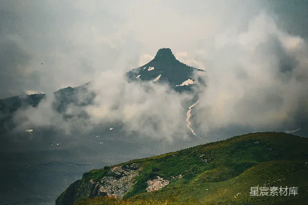 高清摄影 一片绿草覆盖的小山丘，远处有一座山。