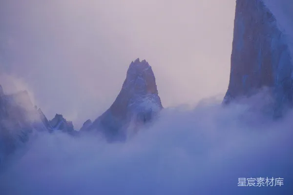 高清摄影 一座被雪和云覆盖的山峰，背景是蓝天。