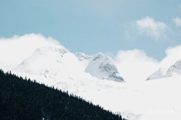 高清摄影 覆盖着积雪的山峰，天空中有几朵云。