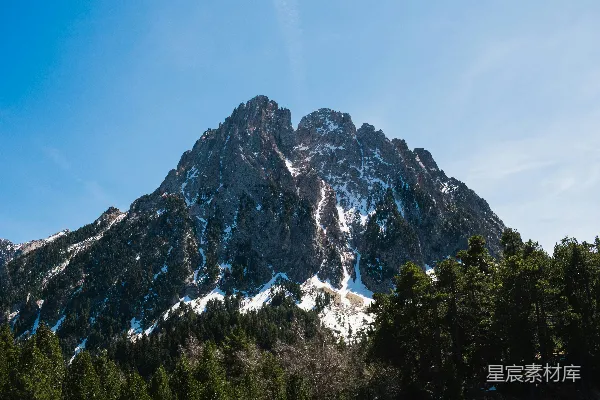 高清摄影 一座覆盖着积雪的山，前景中有树木。