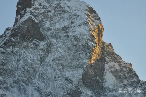高清摄影 白雪覆盖的山峰，一侧沐浴在金色阳光下。
