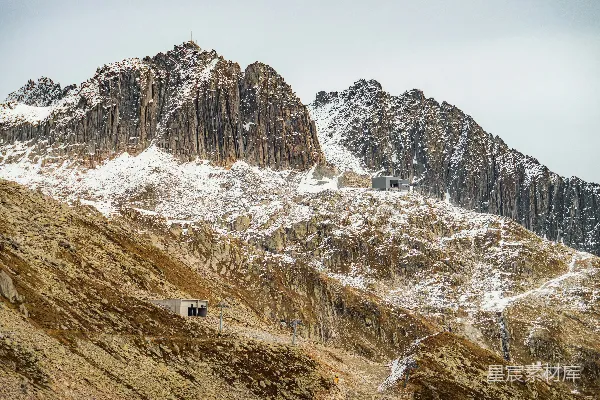 高清摄影 雪覆的岩石山峰在多云的天空下。