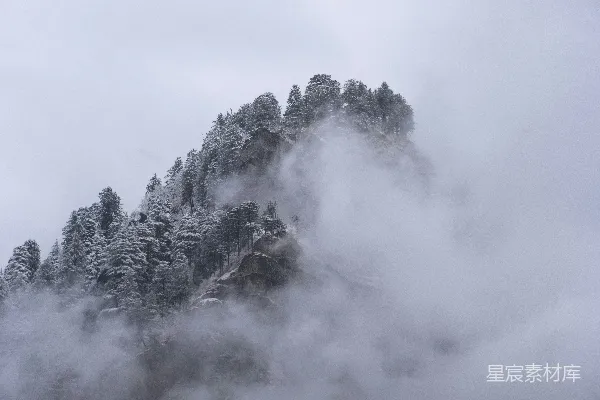 高清摄影 在多云的日子里，一座被雪和雾覆盖的山。