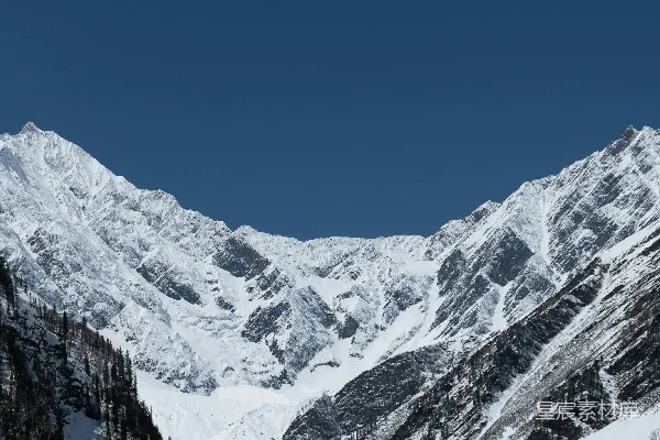 高清摄影 一座被雪覆盖的山，前面有树木。
