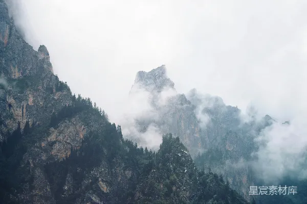 高清摄影 白天，山脚下绿树成荫，白云缭绕。