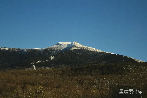 高清摄影 一座覆盖着雪的山峰位于田野中间。