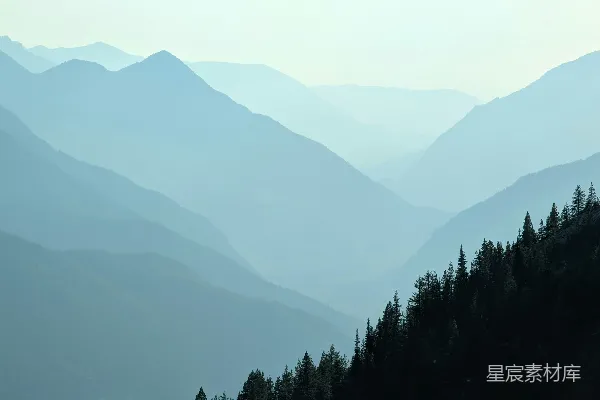 高清摄影 一幅山峦连绵的景色，前景中有树木。