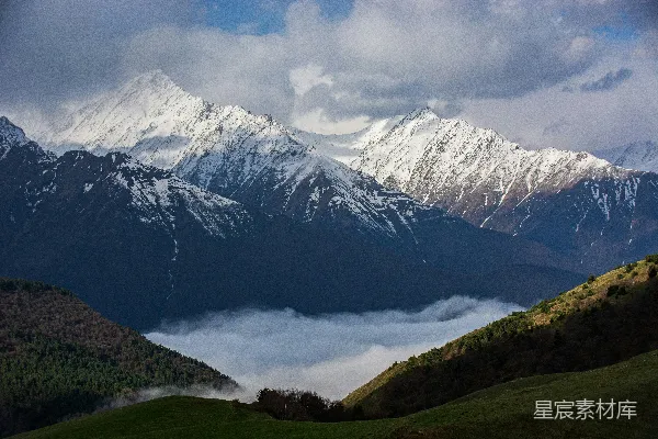 高清摄影 雪山耸立于雾气弥漫的山谷之上。