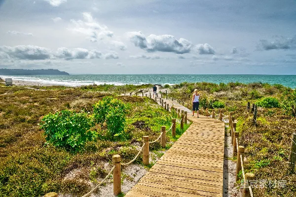 高清摄影 一个人在海滩上的木桥上行走