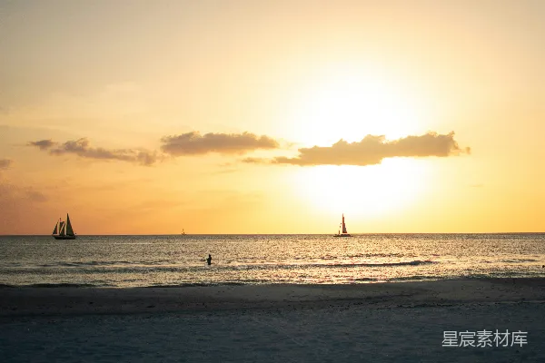 高清摄影 夕阳正照耀着海面，远处可以看到几艘帆船。