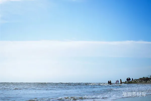 高清摄影 一群人在海滩上，靠近海洋站着。