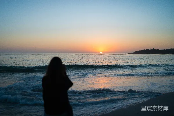 高清摄影 一位女士站在海滩上，夕阳西下。