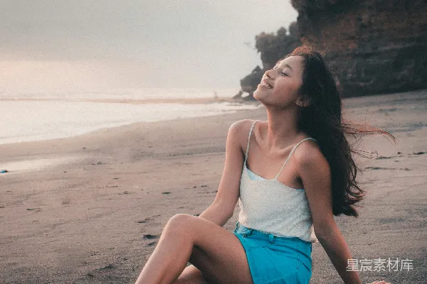 高清摄影 穿着蓝色牛仔短裤的女人坐在海滩岸边，白天。