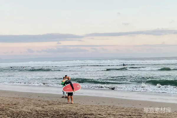 高清摄影 几个人走在海滩上，手里拿着冲浪板。