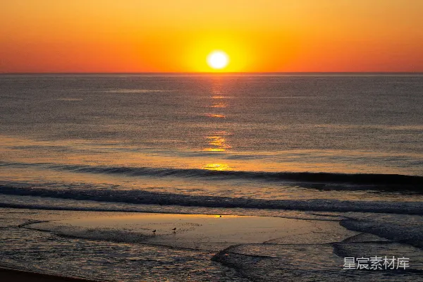 高清摄影 夕阳正洒落在海滩上空的海面上。
