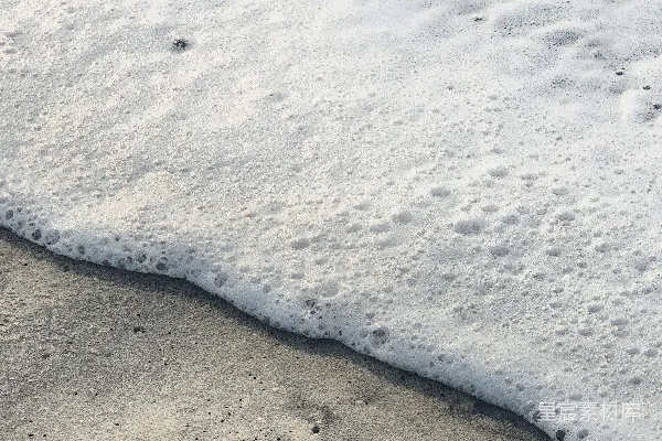 高清摄影 白色的海浪泡沫拍打在沙滩上。