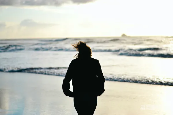 高清摄影 一位女士在日落时分走在海滩上。