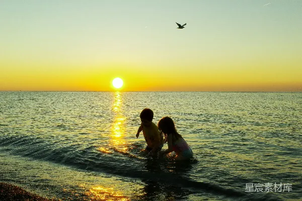 高清摄影 孩子们在夕阳下在海里玩耍。