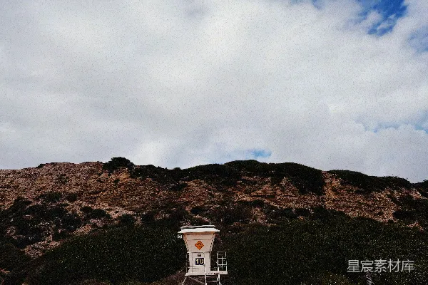 高清摄影 在沙滩上有一座救生员塔，后面是连绵的山丘。