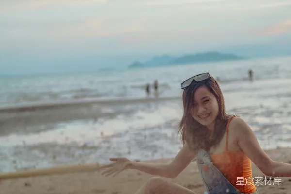高清摄影 穿着红白比基尼的女子在白天坐在海滩岸边。