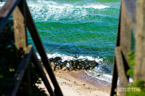 高清摄影 白天，海浪拍打着岸边，棕色的木栏杆矗立在附近。