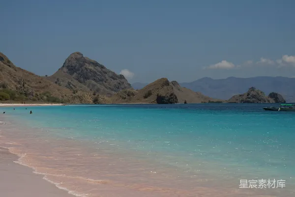 高清摄影 一个沙滩，海水清澈湛蓝，远处是山脉。