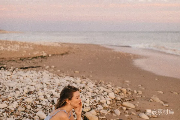 高清摄影 一个女人坐在海滩上，旁边是大海。