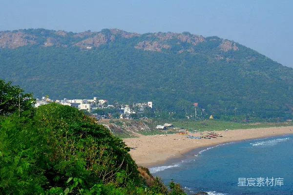 高清摄影 一个海滩场景，有山脉和建筑物。