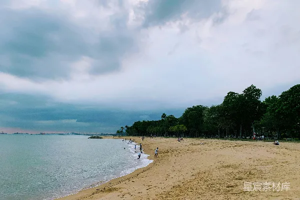 高清摄影 一个沙滩，人们在上面散步，天空多云。