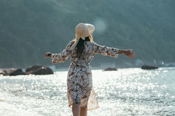 高清摄影 一个女人沿着海滩散步，海浪拍打着岸边。