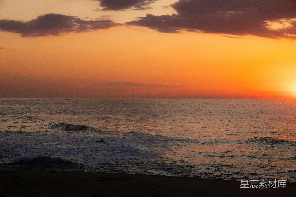 高清摄影 夕阳照耀下的海洋，一个冲浪者在水中