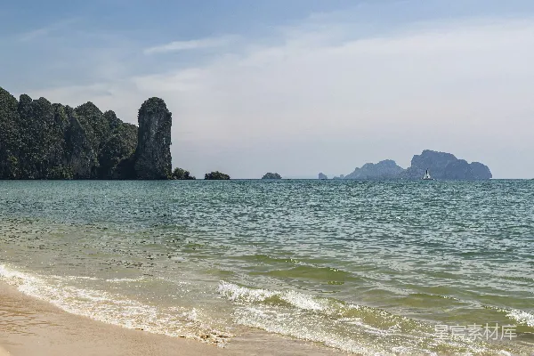 高清摄影 一个沙滩紧邻大海，背景中有山脉。