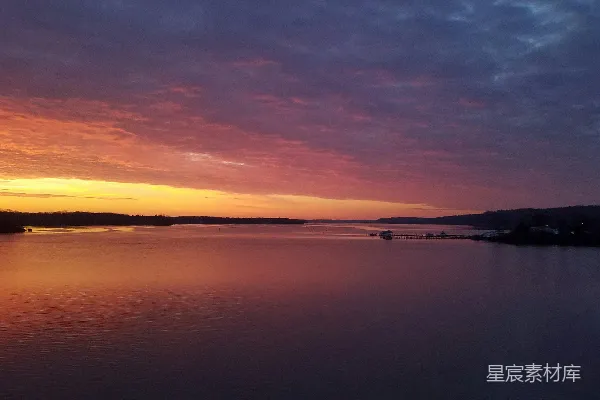 高清摄影 夕阳西下，水面上有一艘船在远处。