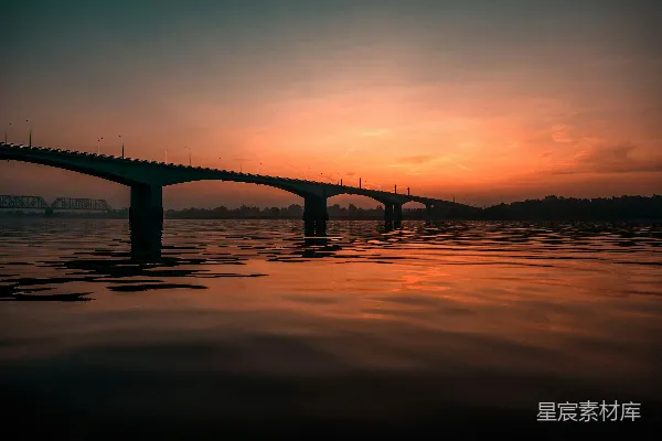 高清摄影 混凝土桥下，橙色的天空映衬着海景。