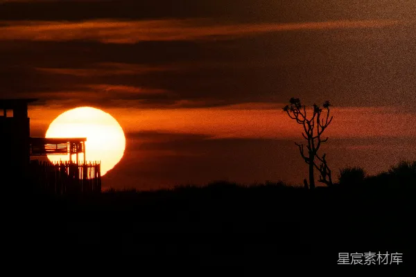 高清摄影 夕阳垂落在一座建筑物的剪影后面。