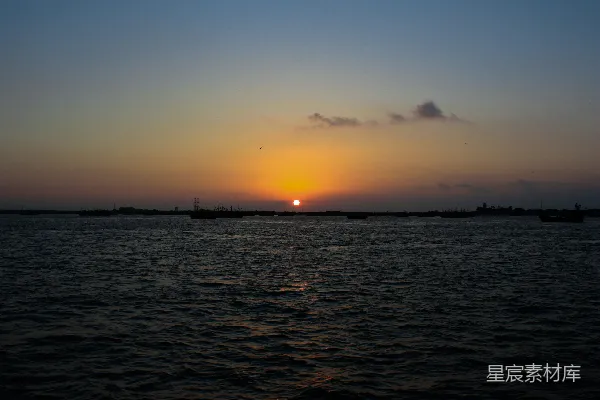 高清摄影 夕阳照耀在水面上，远处有几艘船。