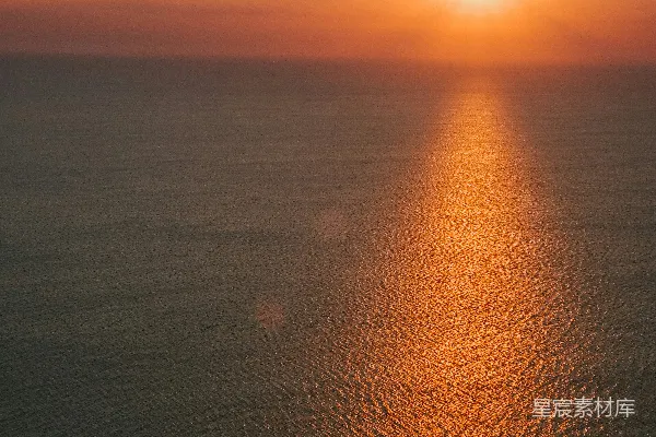 高清摄影 夕阳照耀着平静的海洋，远处有一艘小船。