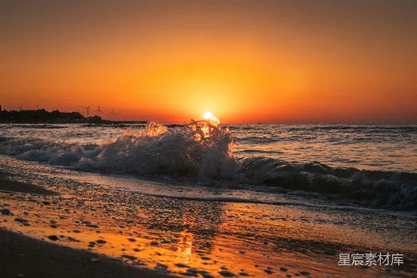 高清摄影 夕阳正缓缓落下，洒落在海滩上的水面上。