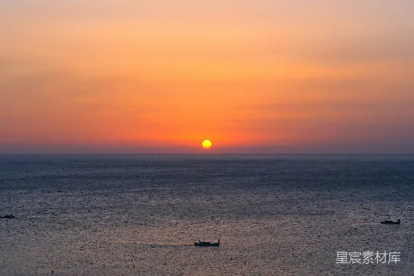 高清摄影 平静的海面上的日落景色，远处有几艘船