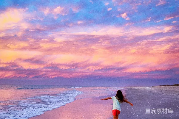 高清摄影 穿着白色连衣裙的女人在日落时分走在海滩上。