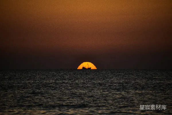 高清摄影 夕阳正缓缓沉入海面，远处有一艘船。