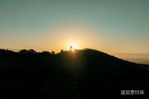 高清摄影 太阳正落在这座山丘上，上面有一个人。