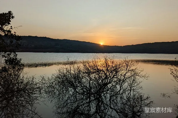 高清摄影 夕阳西下，树木在前景中倒映在湖面上。