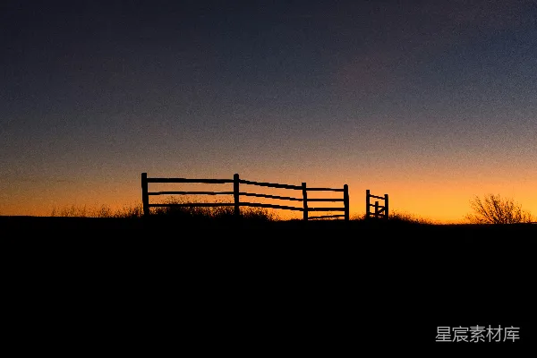 高清摄影 夕阳西下，田野中有一道木栅栏。