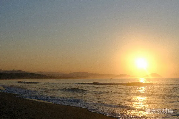 高清摄影 日落时分，海滩上空的夕阳正照在海面上。