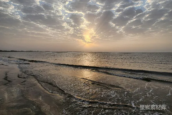 高清摄影 夕阳正挂在海平面上，海滩上。