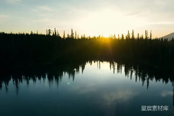 高清摄影 夕阳正在湖边树木环绕的湖面上落下。