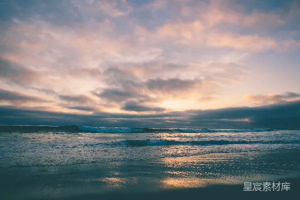 高清摄影 夕阳西下的海滩景色，海浪拍打着海岸线。