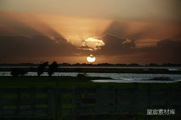 高清摄影 夕阳正缓缓落下，映照在水面上。