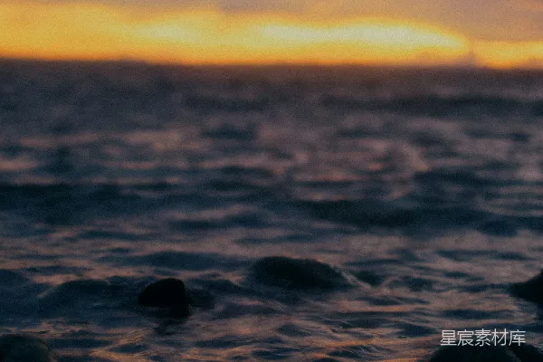 高清摄影 夕阳正缓缓落下，海面上的岩石在前景中显得格外清晰。